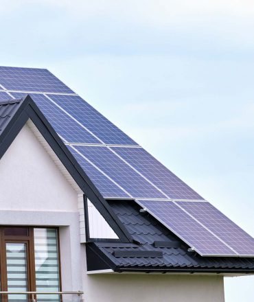 Residential house with rooftop covered with solar photovoltaic panels for producing of clean ecological electrical energy in suburban rural area. Concept of autonomous home